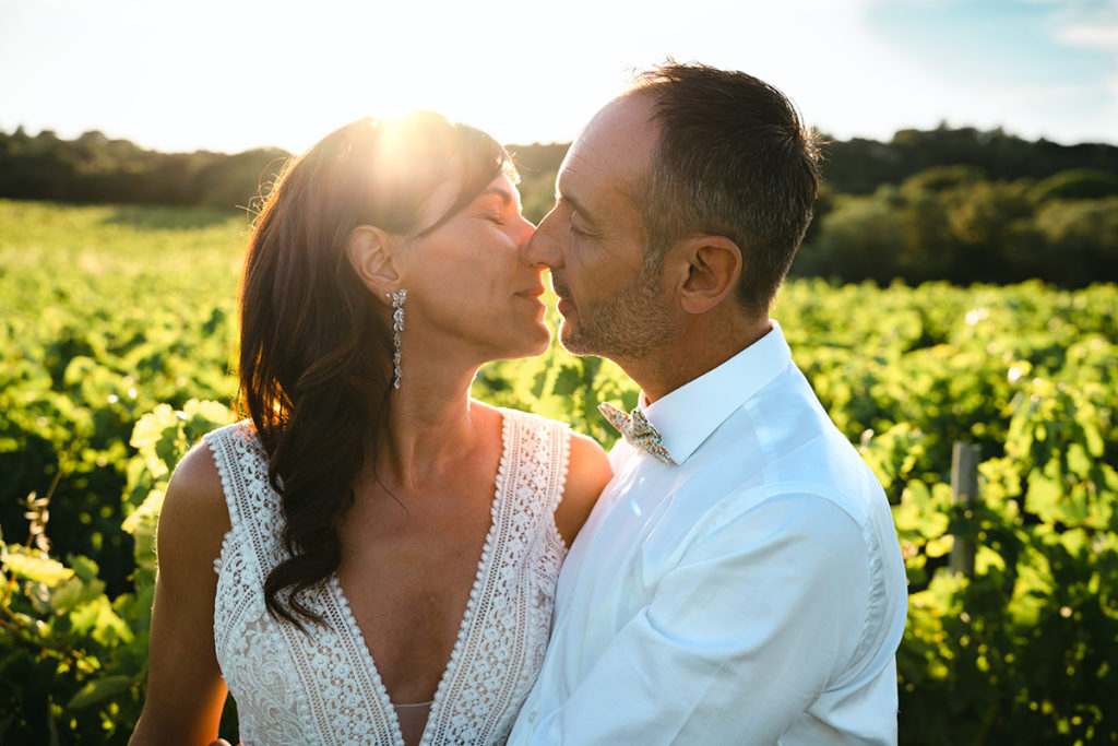 Les mariés s'embrassent au cœur des vignes au coucher du soleil.