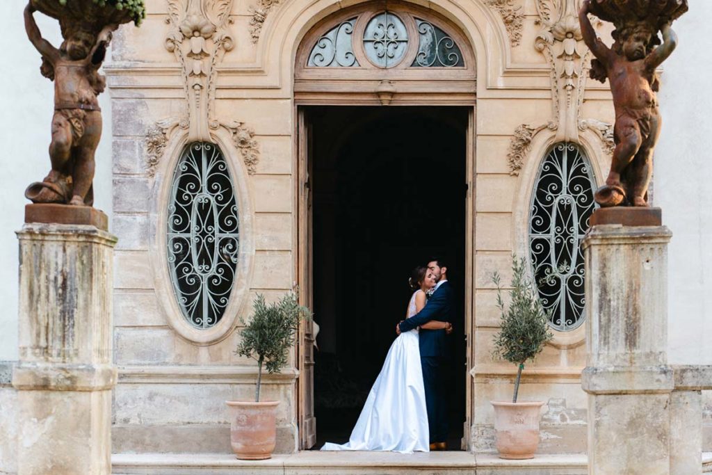Le couple de mariés s'enlace devant les portes du château.
